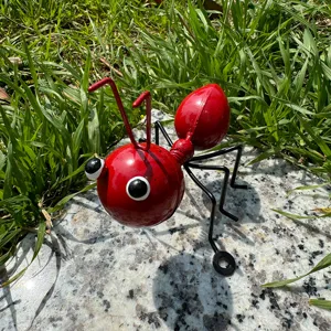 Metal iron ant garden ornament detail shot showing vibrant red body and black legs in natural grass.