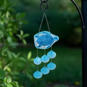 Close-up detail of the glass sea turtle wind chime featuring blue shell pendants outdoor.