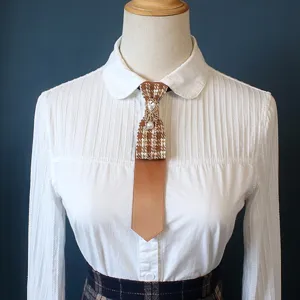 Close-up detail of vintage brown houndstooth necktie with rhinestone and pearl chain accent.