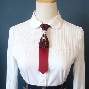 Close-up of a pre-tied burgundy plaid collar tie with pearl chain and rhinestone accent.