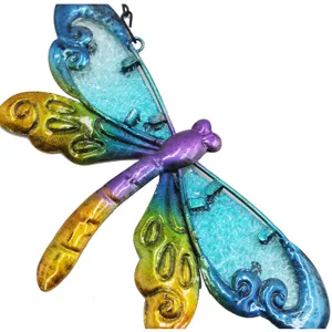Close-up of colorful metal dragonfly hanging ornament with textured glass wings and vibrant paint.