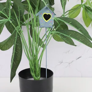 Metal birdhouse garden stake detail showcasing heart-shaped cutout and colorful painted dots.