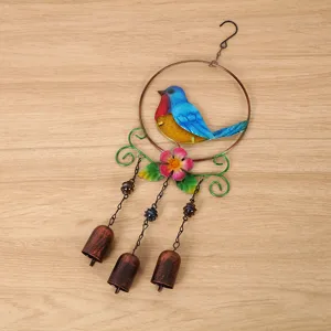 Détail de carillon éolien en métal avec oiseau bleu coloré et trois cloches pour jardin.