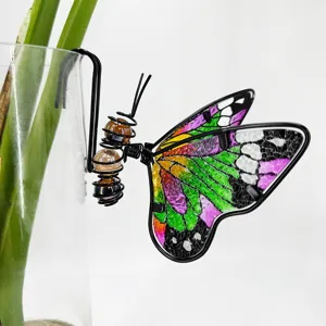 Détail de l'ornement papillon en métal et verre coloré avec un design suspendu.