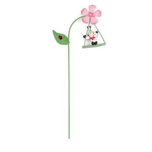 Close-up of metal garden insert featuring a pink flower and cute swinging bug design.