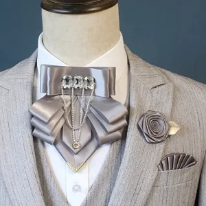 Details van de elegante grijze satijnen strik broche en pocet set met kristallen.