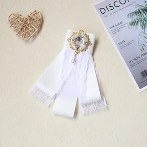 Primo piano della spilla a nastro barocca bianca con pizzo perle e strass scintillanti.