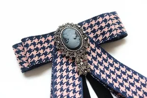 Navy pink houndstooth bow tie featuring vintage cameo brooch, elegant preppy style.