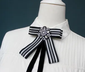 Detailed shot of black and white ribbon bow tie with rhinestone floral center, elegant accessory.