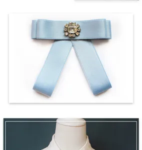 Detailed view of the light blue satin ribbon bow tie with elegant rhinestone brooch center.