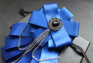 Primo piano della spilla a fiocco blu scuro con montatura in bronzo vintage e catene argentate.