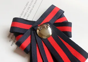 Détail de la broche nœud papillon rayée noir et rouge avec épingle en métal.
