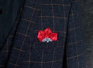 Close-up detail of retro silver carved brooch with black gem and red plaid pocket square.