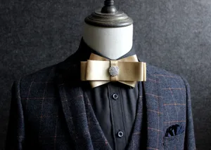 Close-up detail of a luxurious gold layered bow tie with sparkling rhinestone center, formal wear.