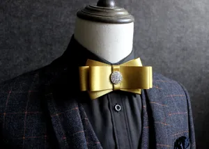 Detail shot of a luxury golden satin bow tie with rhinestone center for men suit.