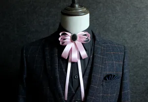 Close-up detail of a pink ribbon bow tie with black rhinestone center on a mannequin suit.