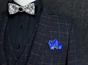 Men's suit brooch detail, decorative bow tie and pocket square accessory set for formal wear.
