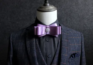 Detailed view of elegant purple satin bow tie with rhinestone center for men wedding formal suit.