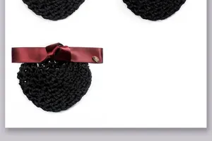 Detailed view of black crochet bun hair net featuring elegant wine-red satin bow and accent.