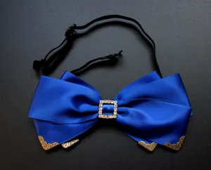 Dettaglio in primo piano del papillon in raso blu con fibbia in strass e angoli in bronzo.