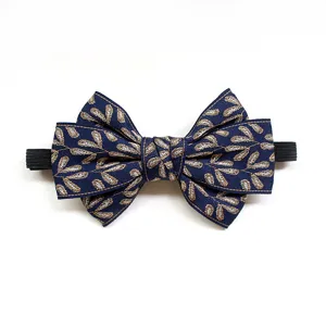 Close up detail view of children navy blue bow tie with golden leaf pattern and elastic band.
