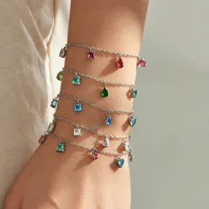 Close-up of layered silver chain bracelets with colorful cubic zirconia charms for women.