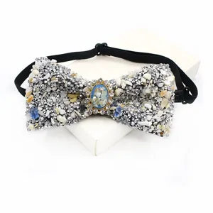 Close-up of sparkling rhinestone and crushed stone bow tie with a central oval gemstone.