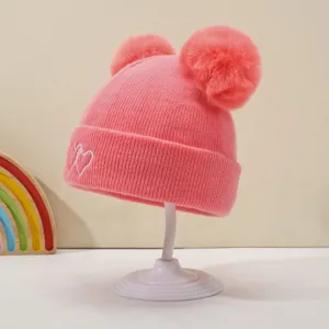 Cute baby knitted winter hat featuring double pom poms and cute heart embroidery for cozy warmth.