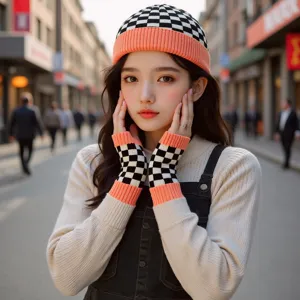 Vue détaillée d'un bonnet en tricot à carreaux noir et blanc et de gants branchés dehors.