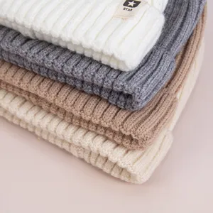 Vista detallada de gorros de invierno de punto para niños apilados en varios colores.