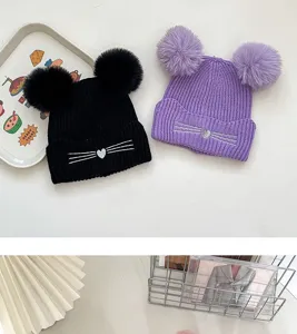 Children winter knit beanie hat with double pom poms and cute cat whisker embroidery details.