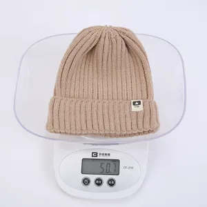 Primer plano de un acogedor gorro de punto de invierno beige colocado en una báscula.