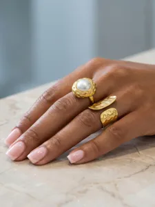 Detail view of gold-plated stainless steel statement rings with pearl and texture design.