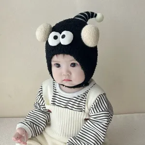 Close-up detail of the cute baby winter plush hat featuring funny eyes and warm earflaps.