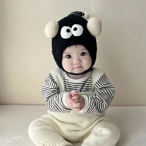 Infant funny big eye plush hat detail view, cute baby wearing thick warm winter earflap cap.