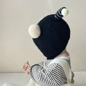 Cute winter baby hat with plush black design, funny ears, and warm earflap protection for infants.