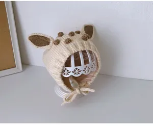 Nahaufnahme des süßen Baby-Strickmütze mit Hirschohren und Bommeln, weiche warme Winterkappe.