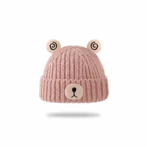 Pink knitted baby beanie hat with cute bear ears and embroidered face for winter warm wear.