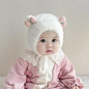 Close-up detail van de dikke pluche baby wintermuts met zachte textuur en schattige roze strikken.