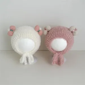 Gedetailleerd overzicht van de schattige dikke pluche baby wintermuts met strik en oorkleppen.
