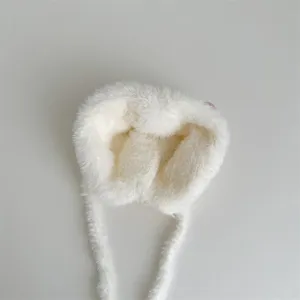 Detailopname van de ultrazachte witte pluche babywintermuts met donzige textuur.