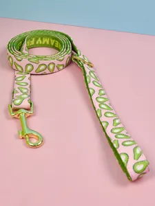 Close-up detail of cute avocado print dog leash with green webbing and gold hardware.
