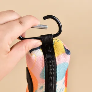 Portable pet poop bag dispenser pouch with colorful abstract print and carabiner clip.