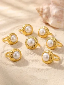 Detailed shot of vintage textured gold rings with pearl inlay, chic aesthetic design jewelry.
