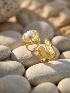 Detailed shot of a stylish gold plated open ring with textured finish and pearl centerpiece.