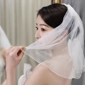 Detail shot of a short bridal veil featuring delicate rhinestones, perfect for wedding photography.