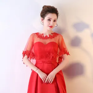 Detail de la cape de mariee en dentelle rouge et de la robe de soiree elegante.