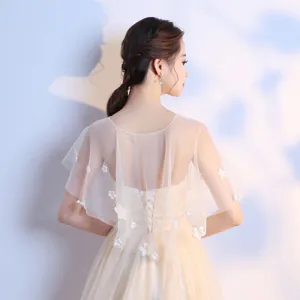 Dettaglio mantellina da sposa in tulle trasparente con delicate decorazioni floreali 3D.