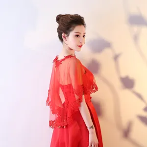 Détail de cape de mariée en dentelle rouge montrant un tissu en maille transparente et broderie.