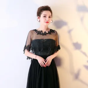 Détail de cape en dentelle noire avec broderie florale délicate et tissu en tulles.